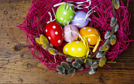 A vibrant nest made of pink twigs holds colorful Easter eggs with polka dots, set against a rustic wooden background, capturing the essence of the holiday in a stunning HD wallpaper.