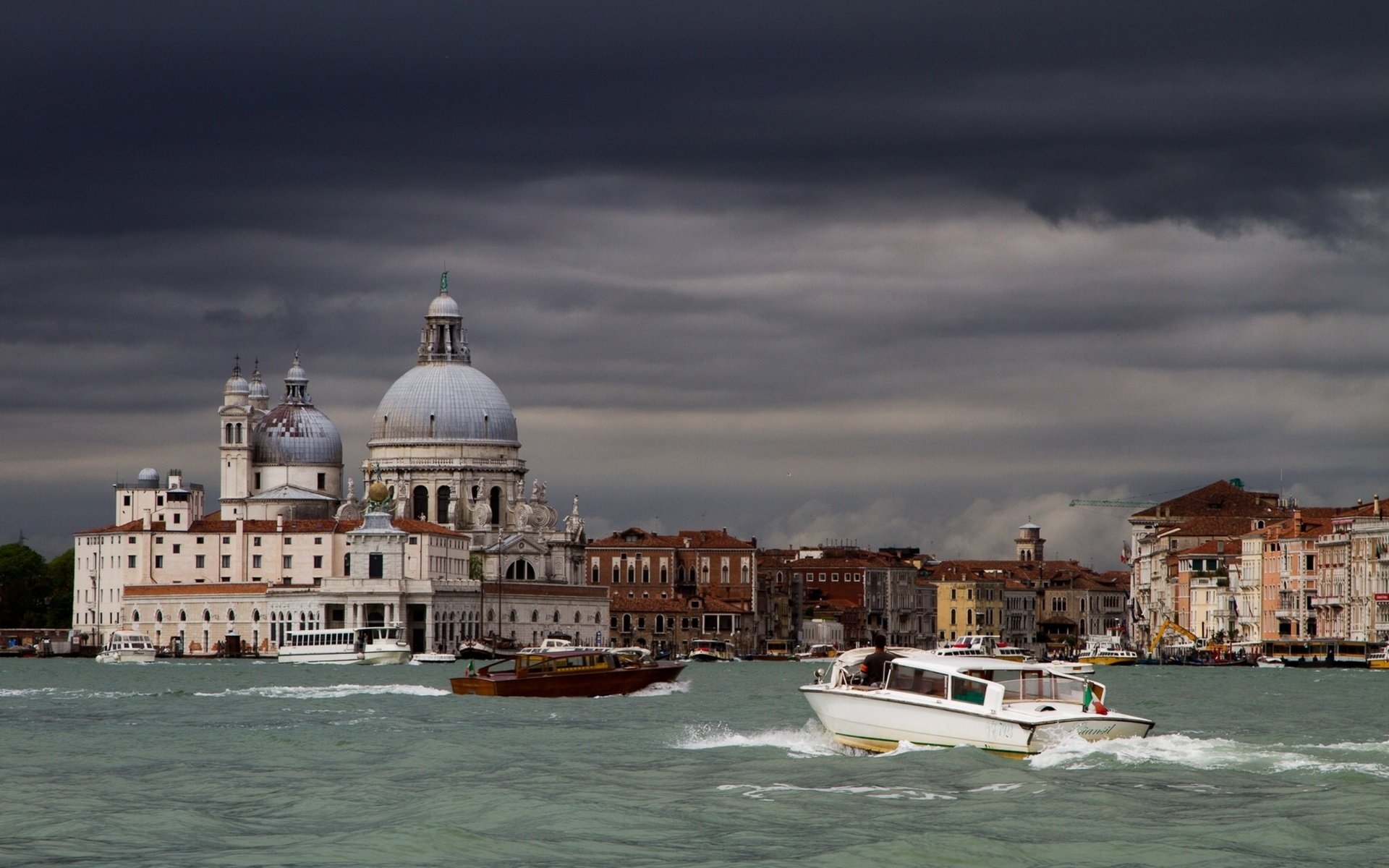 Venice HD PC desktop wallpaper background: man-made domed basilica and historic waterfront, motorboats cutting through choppy water beneath a dramatic, cloud-filled sky.