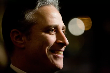 HD desktop wallpaper featuring a smiling man in the style of The Daily Show with Jon Stewart with a blurred background.