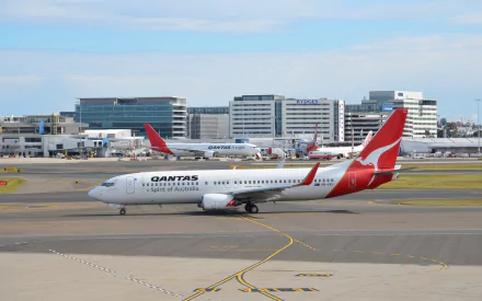 A Qantas Boeing 737 aircraft at Sydney Airport, showcasing the impressive airport backdrop and dynamic aviation scene. A vibrant HD wallpaper for airplane enthusiasts.