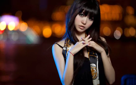 HD desktop wallpaper featuring a female model with long black hair, posing at night with blurred city lights in the background.