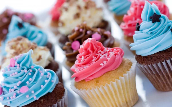 HD PC desktop wallpaper featuring an array of colorful cupcakes with vibrant blue and pink frosting decorated with sprinkles and stars.