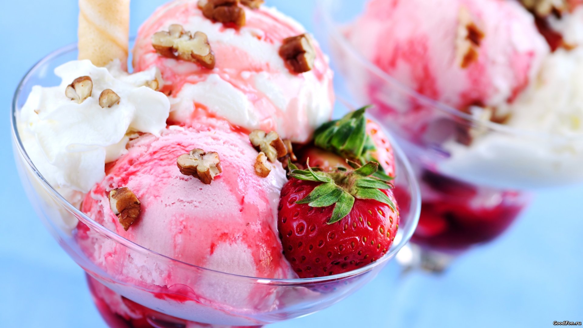 HD desktop wallpaper featuring scoops of delicious strawberry ice cream topped with whipped cream, walnuts, and fresh strawberries. The background is blurred to highlight the vibrant dessert.