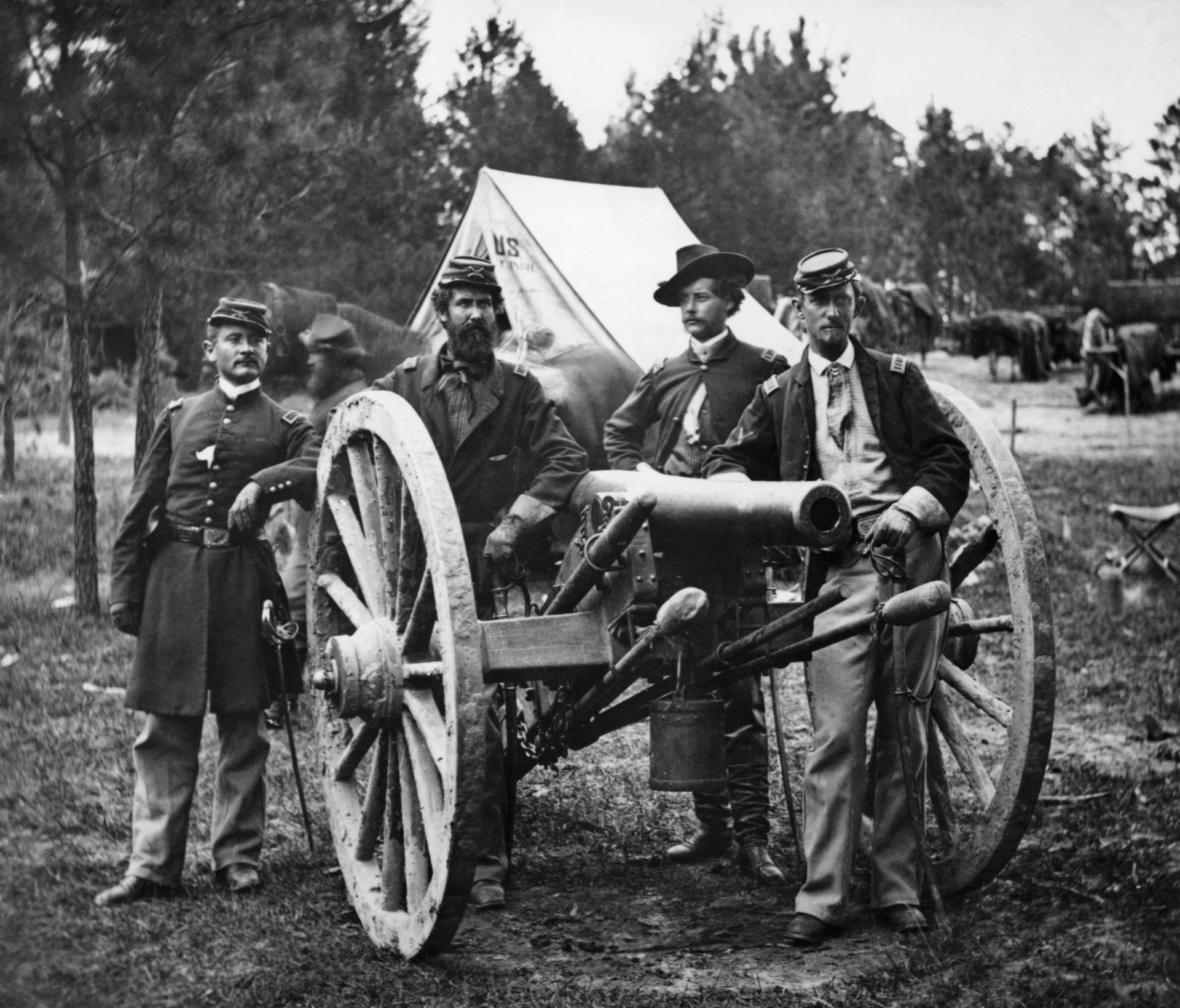 Black and white HD desktop wallpaper showing five military men standing around a large artillery cannon in a forested camp.
