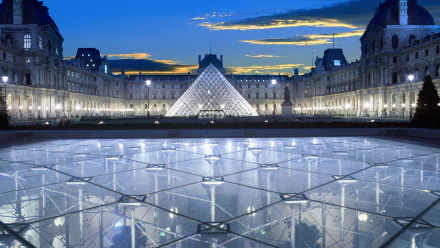 A stunning view of The Louvre in Paris at dusk, showcasing the iconic glass pyramid illuminated against a vibrant evening sky. The reflection pool adds depth to this architectural marvel.