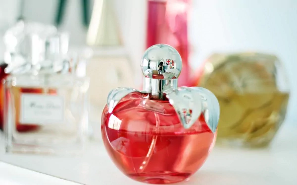 A beautifully styled perfume bottle in the foreground, showcasing vibrant colors and elegant design, with other bottles softly blurred in the background, creating an artistic and sophisticated desktop wallpaper.