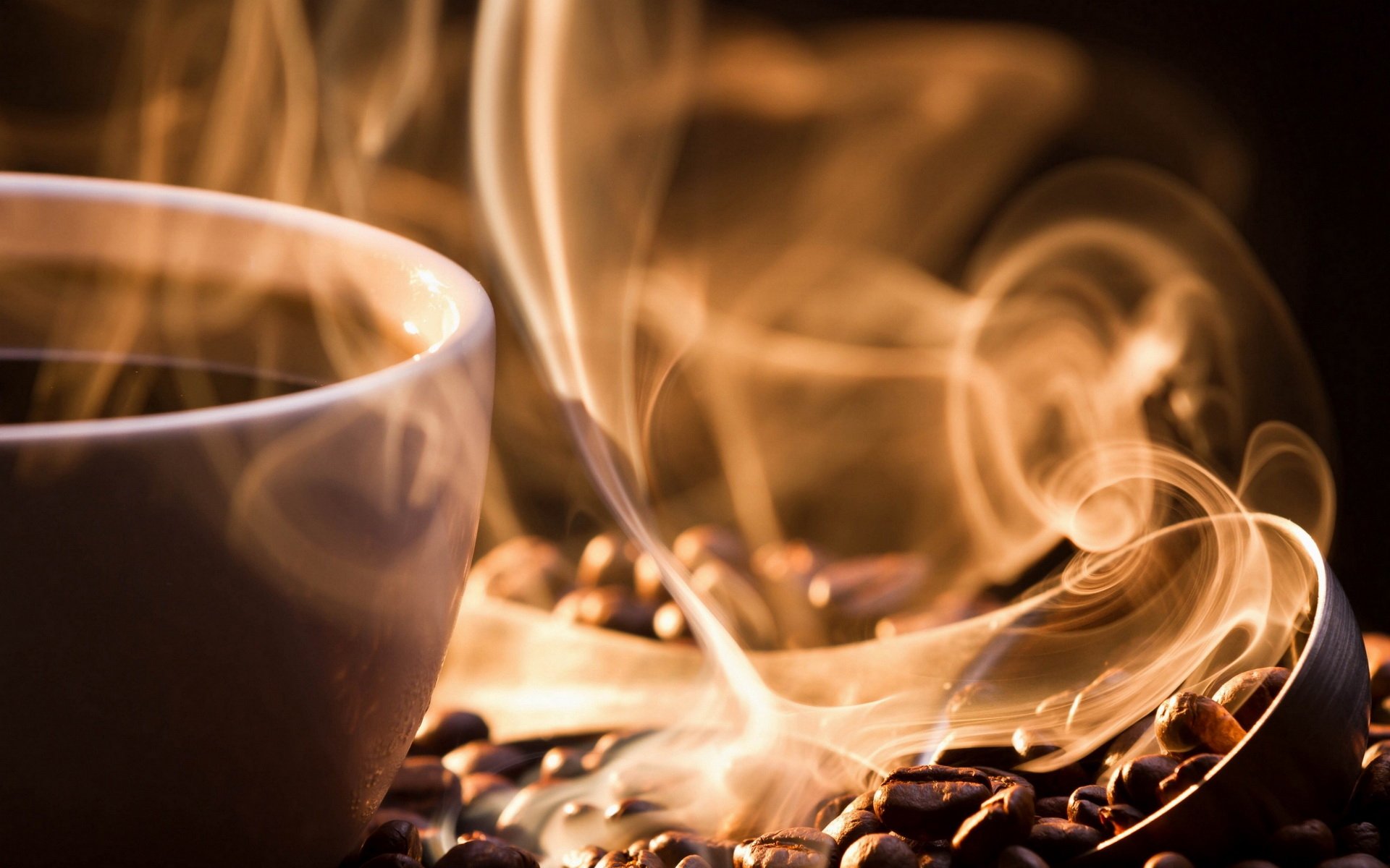 A steaming cup of coffee sits amidst scattered coffee beans, with wisps of smoke rising gently, creating a warm and inviting atmosphere. HD desktop wallpaper and background.