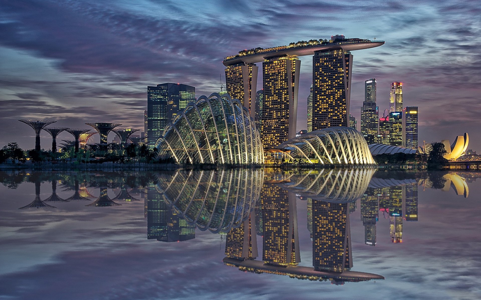 HD photography PC desktop wallpaper: Marina Bay Sands and Gardens by the Bay skyline at dusk, glowing lights mirrored in calm water reflection.