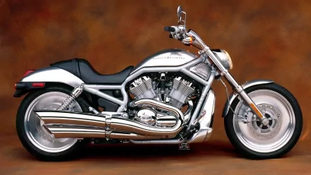 HD desktop wallpaper featuring a sleek silver Harley-Davidson V-Rod motorcycle against a warm brown background.
