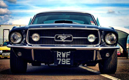A classic Ford Mustang showcased in a striking HD desktop wallpaper, featuring its iconic front grille and sleek design against a blue sky backdrop.
