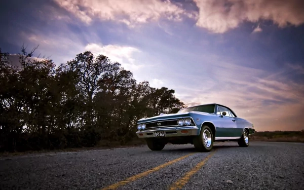 A striking Chevrolet Chevelle SS muscle car parks along a scenic road, surrounded by trees under a dramatic sky, making for an impressive HD desktop wallpaper.