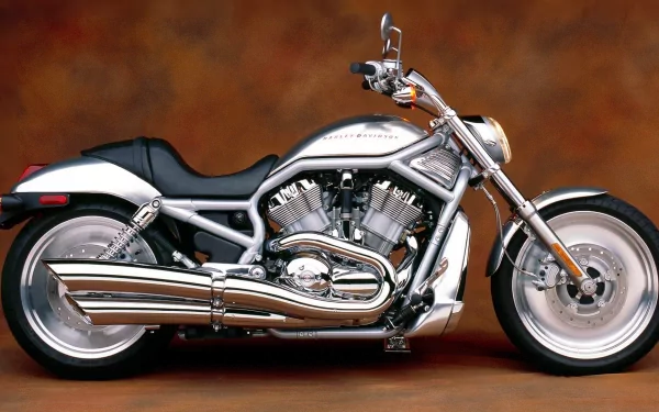 HD desktop wallpaper featuring a sleek silver Harley-Davidson V-Rod motorcycle against a warm brown background.