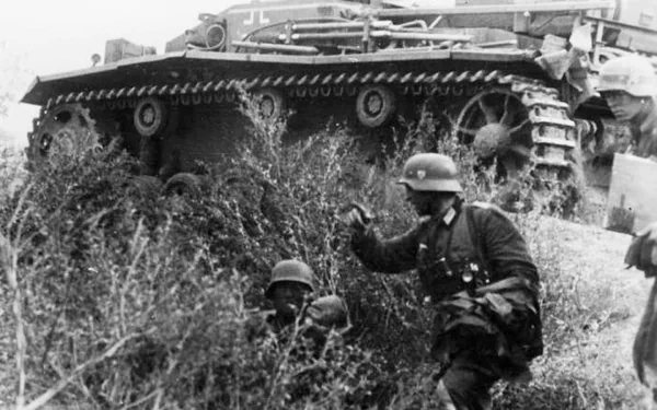 Black-and-white military HD PC desktop wallpaper: Sturmgeschütz III assault gun with infantry in tall grass, wartime battlefield scene.