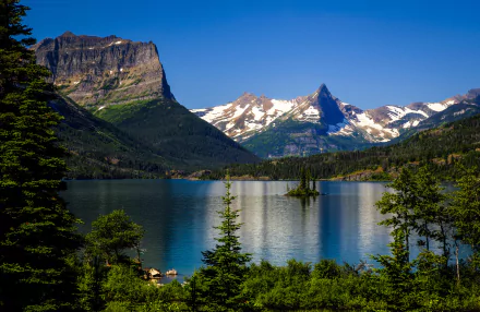 A serene view of a lake surrounded by towering mountains and lush trees in Glacier National Park, showcasing the beauty of nature in an HD desktop wallpaper.