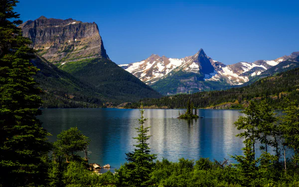 A serene view of a lake surrounded by towering mountains and lush trees in Glacier National Park, showcasing the beauty of nature in an HD desktop wallpaper.