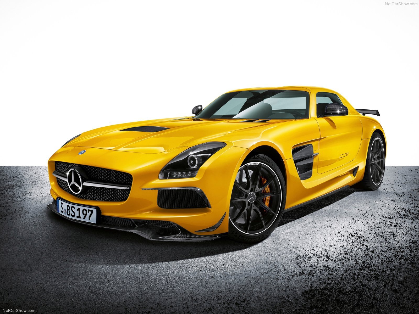 HD desktop wallpaper featuring a vibrant yellow Mercedes-Benz SLS AMG sports car on a textured gray surface with a white background.