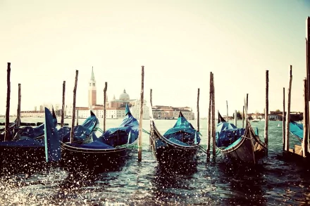 HD desktop wallpaper showing several canoes moored on calm water with a cityscape and clear sky in the background.