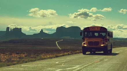 HD desktop wallpaper featuring a school bus on a road with a scenic mountainous backdrop.