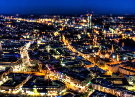 HD desktop wallpaper of Frankfurt, Germany — aerial nighttime view of a man-made cityscape with glowing streets, lit skyscrapers and river reflections.