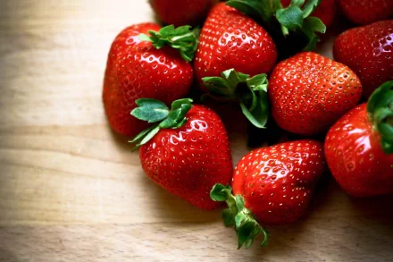 HD PC desktop wallpaper featuring a close-up of fresh, ripe strawberries on a wooden surface, highlighting their vibrant red color and green leaves.