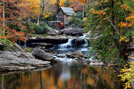 A serene watermill surrounded by vibrant autumn foliage, with gentle waterfalls cascading into a tranquil pool, showcased in stunning 4K Ultra HD detail.