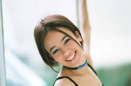 HD PC desktop wallpaper featuring a smiling Alizée, capturing a bright and joyful moment in a soft, natural setting with a light, blurred background.