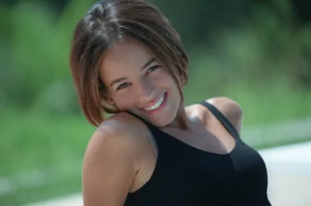 A vibrant HD desktop wallpaper featuring Alizée, smiling brightly against a green background, radiating joy and a lively spirit.