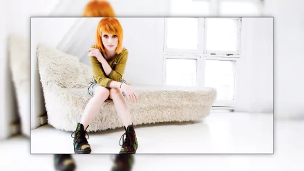 HD PC desktop wallpaper featuring Hayley Williams seated in a bright, minimalist room, emphasizing her vibrant hair and distinctive style in a music-themed image.