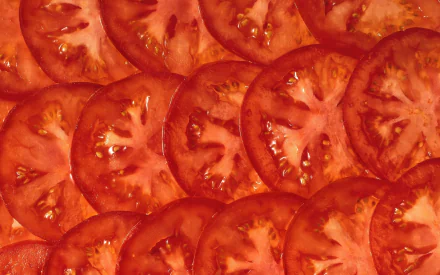 HD PC desktop wallpaper featuring a vibrant close-up of fresh, sliced tomatoes showcasing their juicy texture and rich red color.