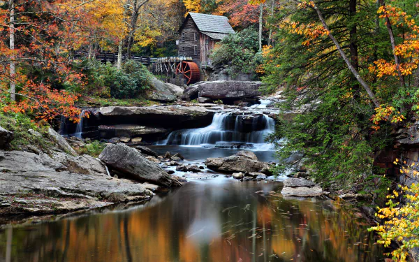 A serene watermill surrounded by vibrant autumn foliage, with gentle waterfalls cascading into a tranquil pool, showcased in stunning 4K Ultra HD detail.