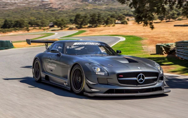HD PC desktop wallpaper featuring a sleek Mercedes-Benz SLS AMG racing on a winding track surrounded by dry grass and trees.