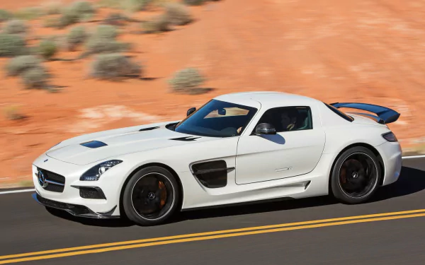 White Mercedes-Benz SLS AMG sports car driving on a desert highway, captured in a high-definition PC desktop wallpaper.