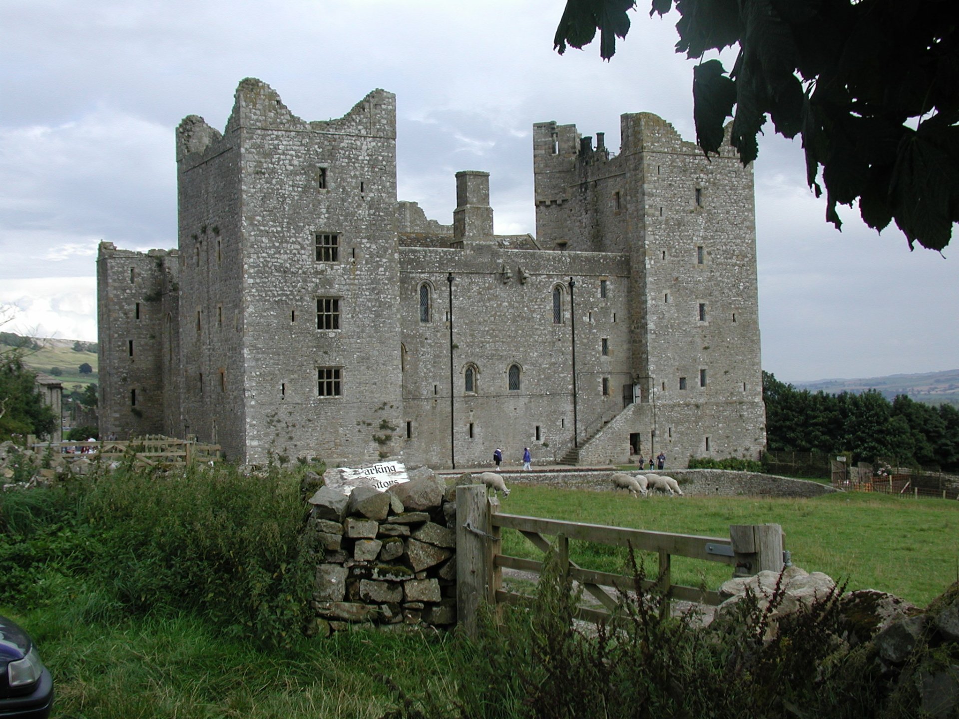 HD PC desktop wallpaper and background showing Bolton Castle, a man-made medieval stone fortress amid green lawns, dry-stone walls and a cloudy sky.
