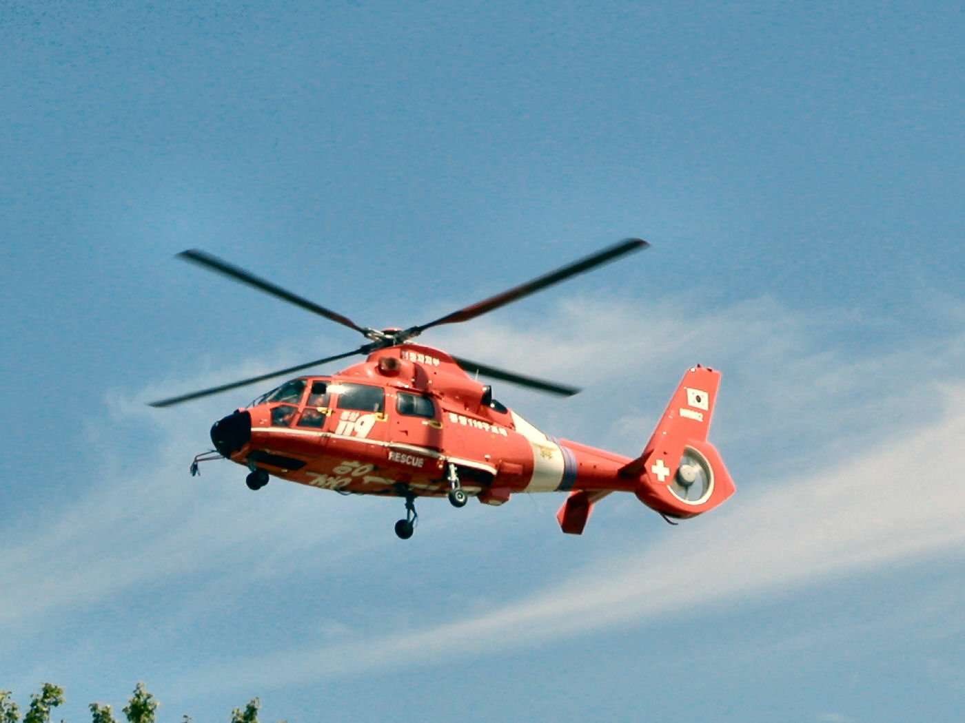 Red Eurocopter AS365 Dauphin helicopter (air vehicle) in flight against a blue sky; HD PC desktop wallpaper and background.