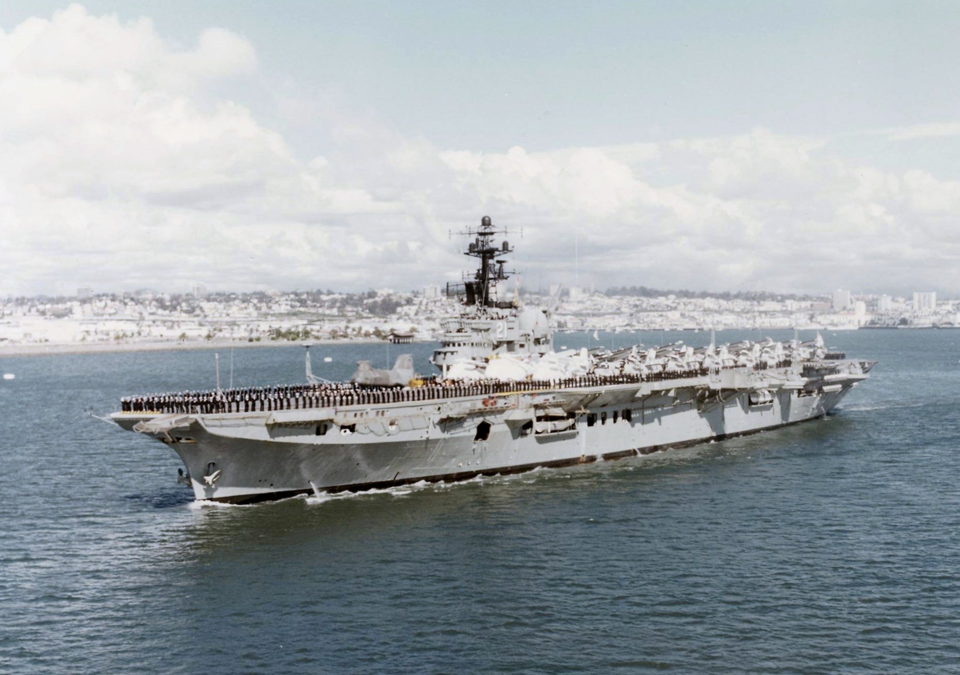 HD PC desktop wallpaper showing the military aircraft carrier HMAS Melbourne (R21) underway at sea — a warship with flight deck and superstructure against a coastal skyline.
