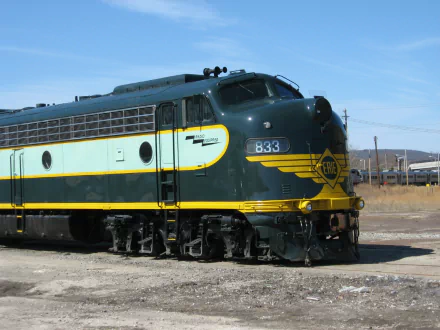 HD PC desktop wallpaper/background of a green-and-yellow diesel locomotive train parked on sunlit tracks beneath a clear blue sky.
