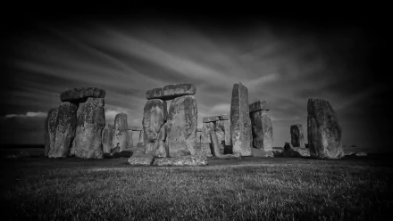 A dramatic black and white HD desktop wallpaper featuring the iconic stone structure of Stonehenge, set against a moody sky, capturing the ancient monument's grandeur.