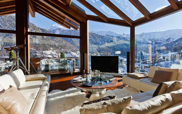 HD PC desktop wallpaper featuring a man-made room with large glass windows overlooking snowy mountains, furnished with modern sofas and a central coffee table.