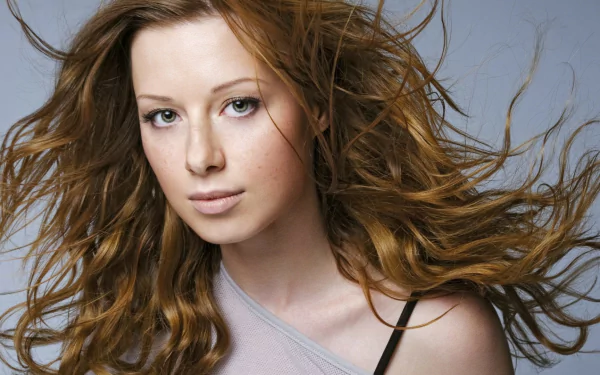 HD desktop wallpaper featuring musician Yulia Savicheva with flowing hair against a gray background, highlighting her natural look and expressive gaze.