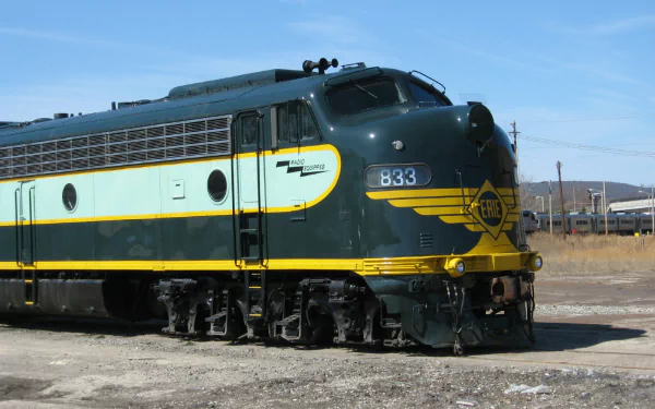 HD PC desktop wallpaper/background of a green-and-yellow diesel locomotive train parked on sunlit tracks beneath a clear blue sky.