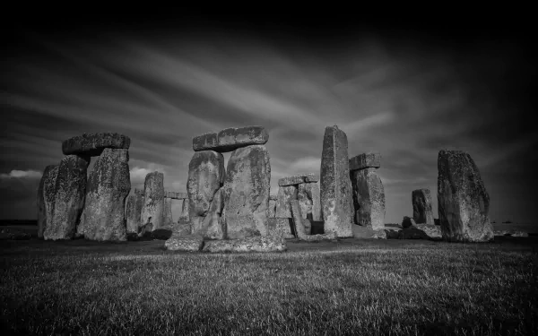 A dramatic black and white HD desktop wallpaper featuring the iconic stone structure of Stonehenge, set against a moody sky, capturing the ancient monument's grandeur.