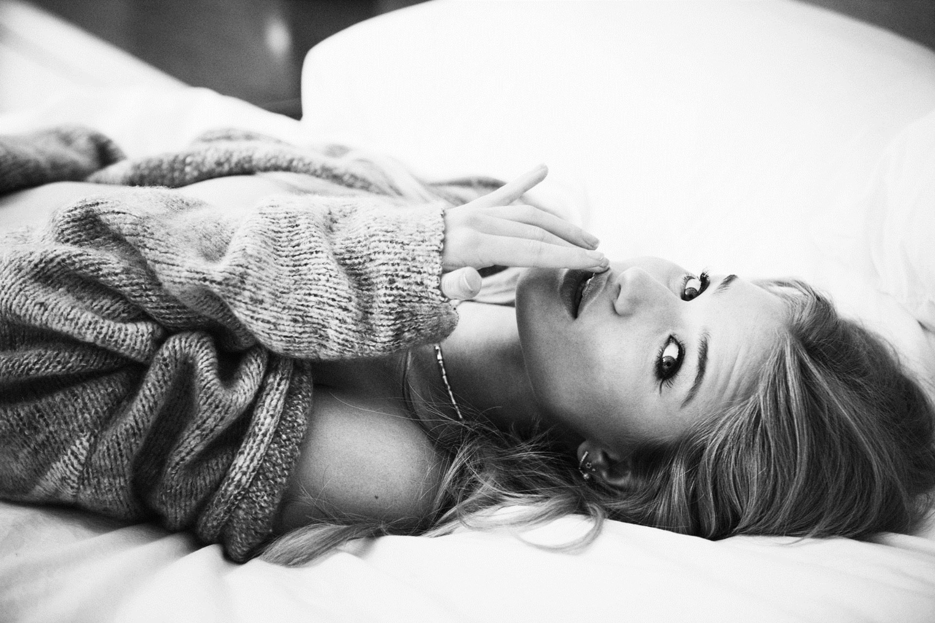 Black and white HD PC desktop wallpaper featuring celebrity Rosie Huntington-Whiteley reclining and gazing at the camera in a cozy sweater.