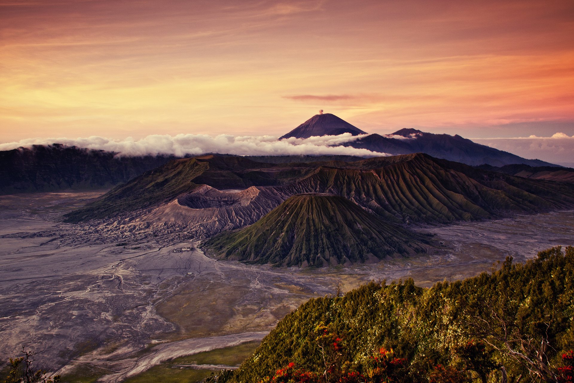 HD PC desktop wallpaper featuring a vibrant nature landscape with layered volcanic mountains under a glowing sunset sky.