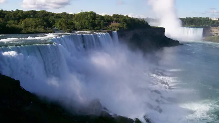 Niagara Falls in HD, showcasing the powerful cascades and misty surroundings, with lush greenery in the background. This nature-themed desktop wallpaper captures the majestic beauty of the falls.