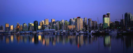HD desktop wallpaper featuring the Vancouver skyline at dusk, with illuminated buildings reflected in the calm waters of the harbor.