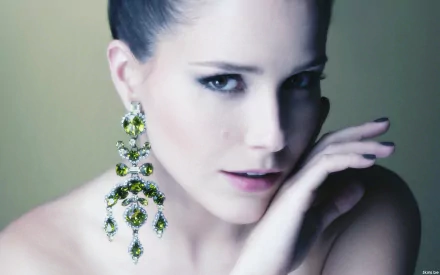 HD PC desktop wallpaper featuring celebrity Sophia Bush with elegant makeup and large, ornate green and gold earrings against a soft, muted background.