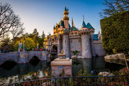 HD desktop wallpaper of Disneyland's iconic castle, captured in beautiful light with reflections on the surrounding moat.