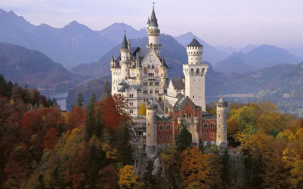 A stunning HD desktop wallpaper featuring Neuschwanstein Castle, beautifully surrounded by autumn foliage and majestic mountains. A captivating blend of nature and architecture.