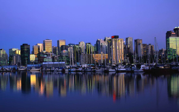 HD desktop wallpaper featuring the Vancouver skyline at dusk, with illuminated buildings reflected in the calm waters of the harbor.