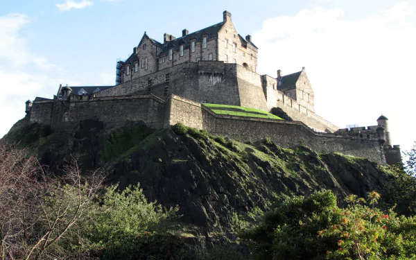 HD desktop wallpaper of Edinburgh Castle, a historic man-made fortress perched atop a rocky hill with clear skies in the background.